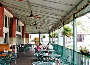 carroll architectural shade an outdoor dining area is enclosed by roll-up curtains, currently rolled up