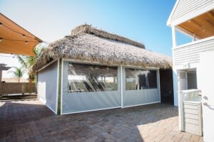 carroll architectural shade retractable screens with clear windows pulled down under a beachside hut