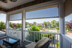 carroll architectural shade retractable shade screens pulled down slightly around a waterfront porch