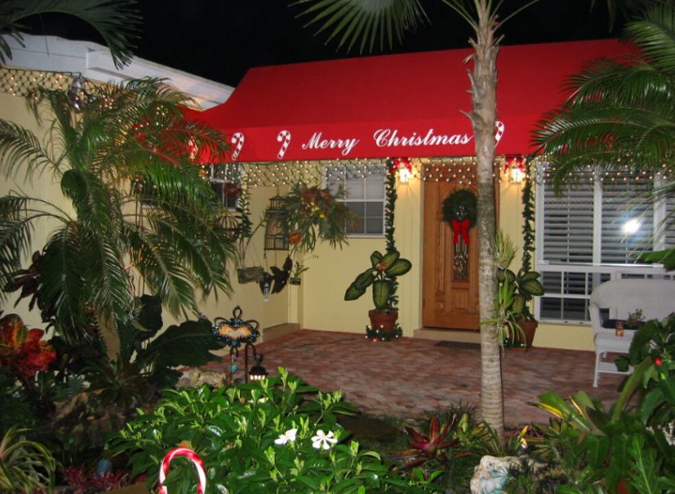 a home awning that reads "Merry christmas" and has string lights hanging around the edge